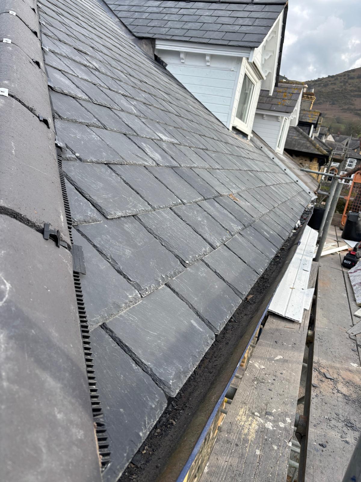 Completed natural slate roof with neat ridge tiles and lead detailing