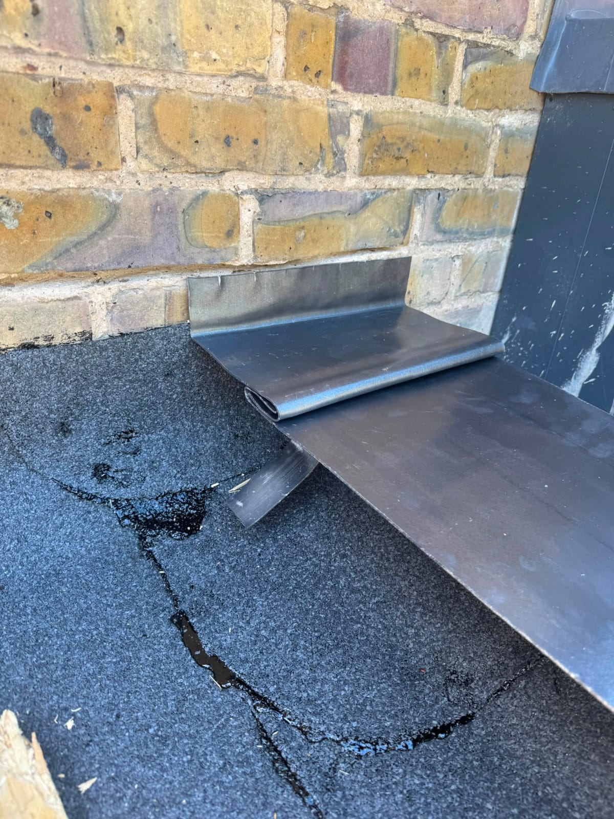 Lead flashing being dressed in around a chimney by a roofer