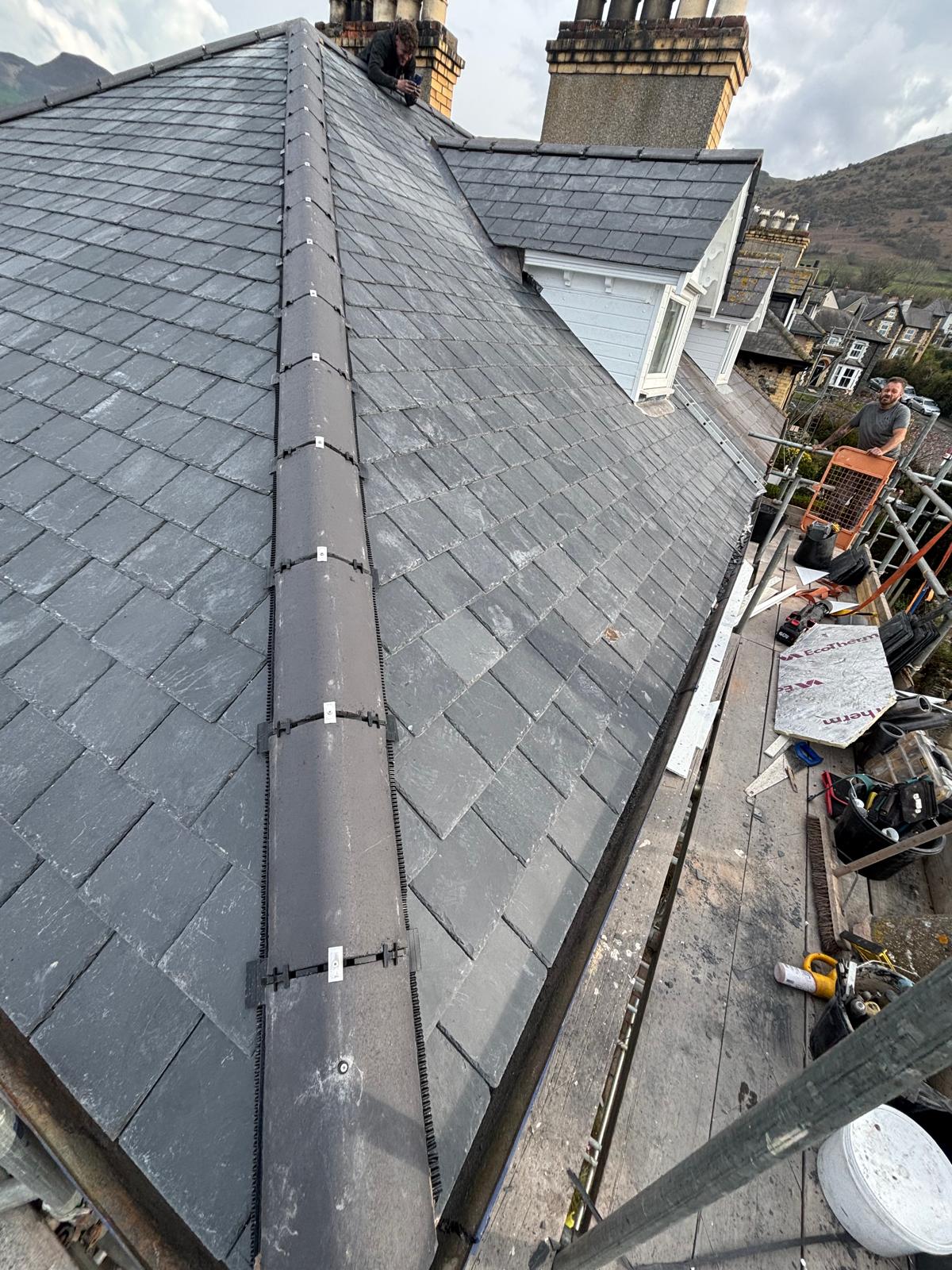 Completed natural slate roof with neat ridge tiles and lead detailing