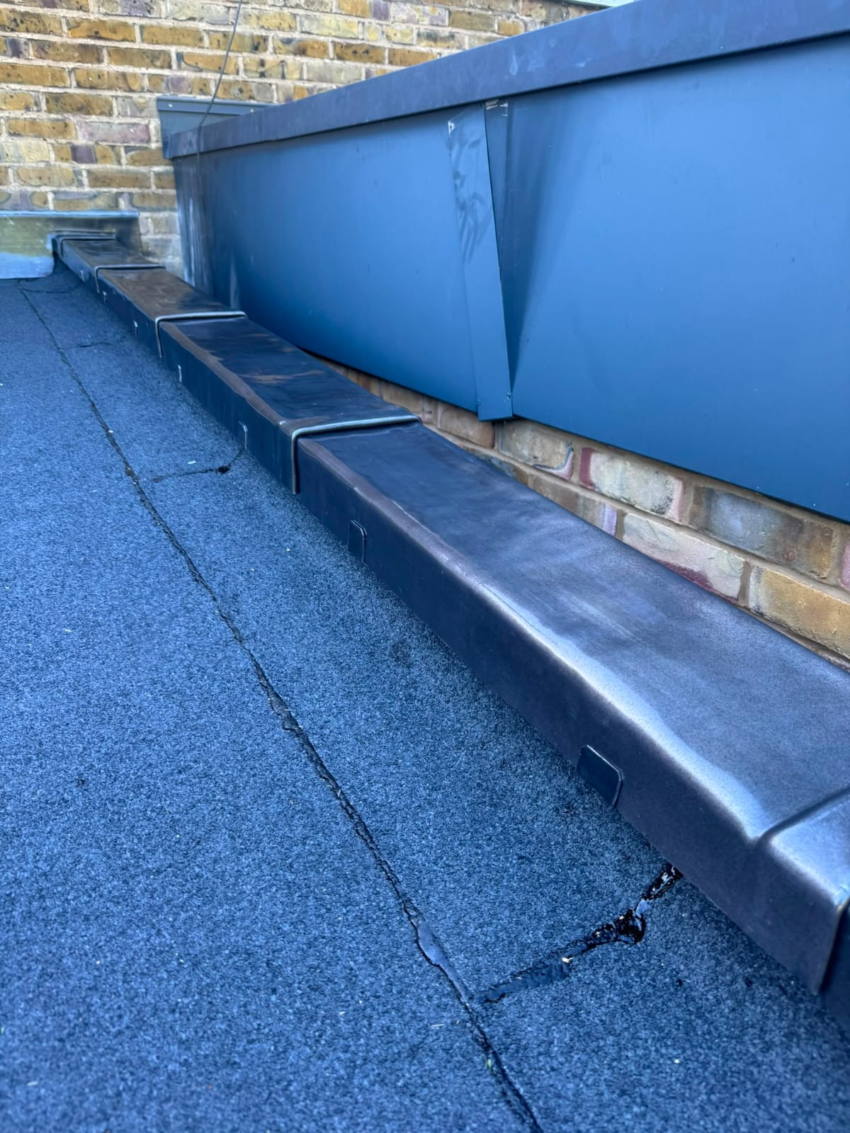New lead flashing and lead-lined parapet gutter dressed against brickwork