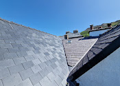 Completed natural slate roof with neat ridge tiles and lead detailing
