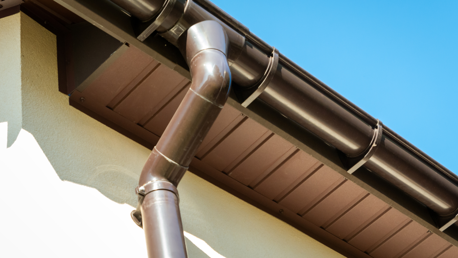 New black uPVC guttering and downpipe fitted to the eaves of a stone house