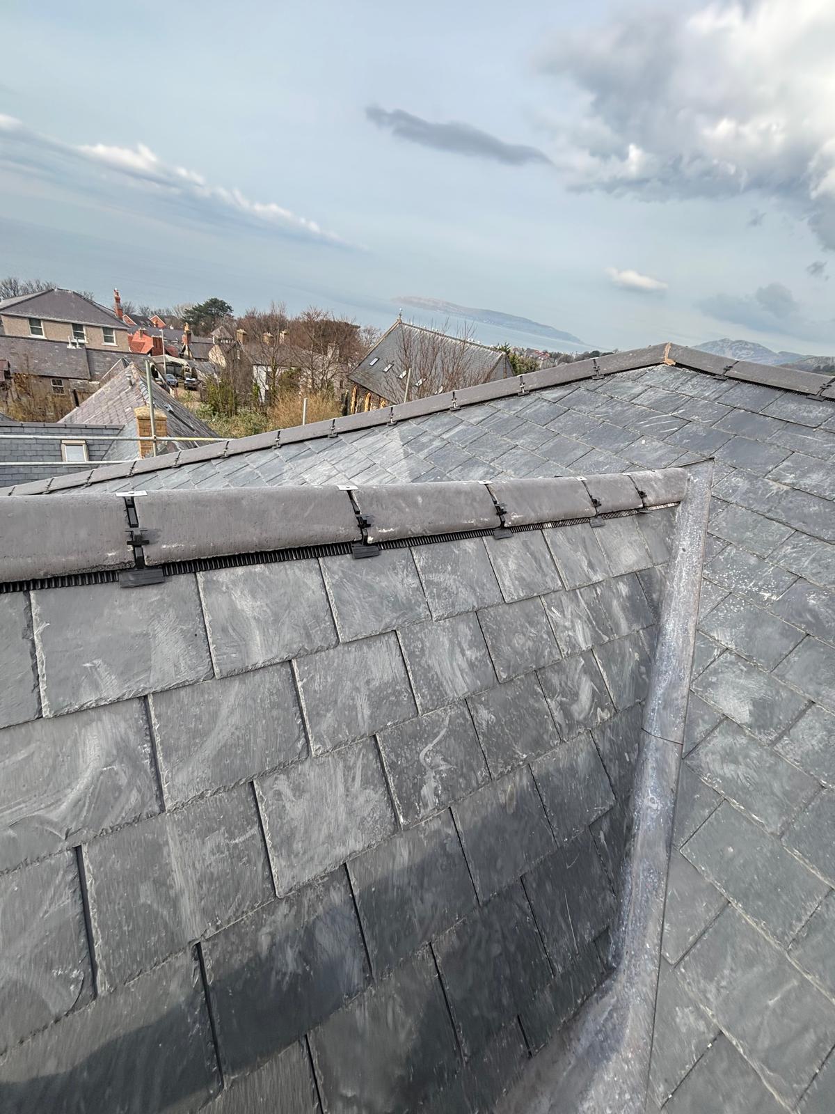 Completed natural slate roof with neat ridge tiles and lead detailing