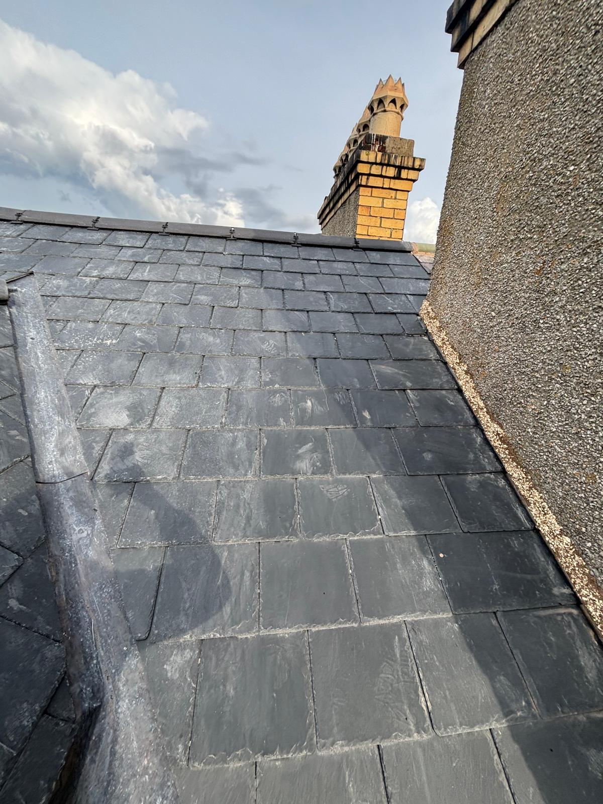 Completed natural slate roof with neat ridge tiles and lead detailing