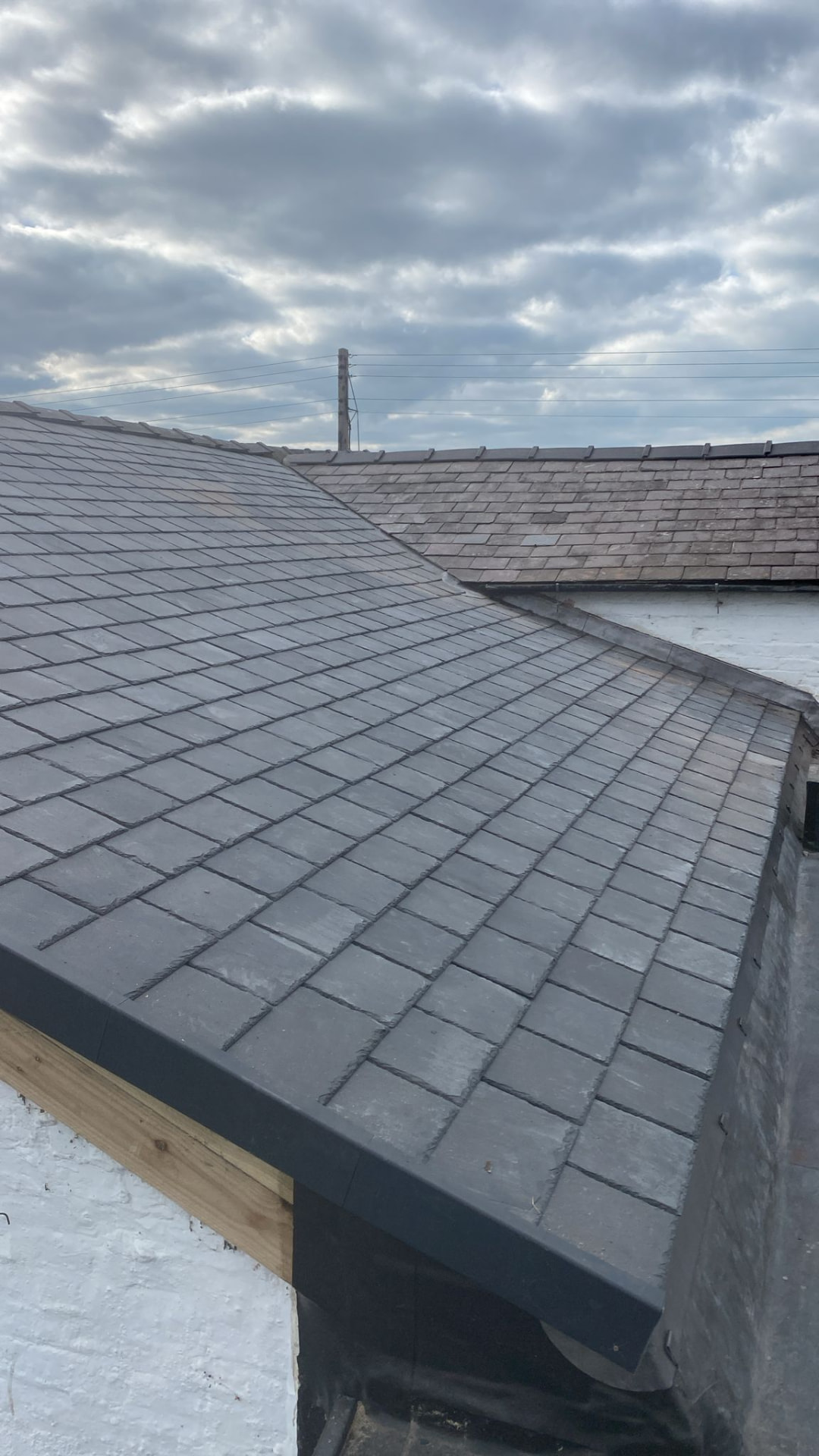 Completed natural slate roof with neat ridge tiles and lead detailing